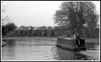 A black and white photo of a canal boat flowing from right to left