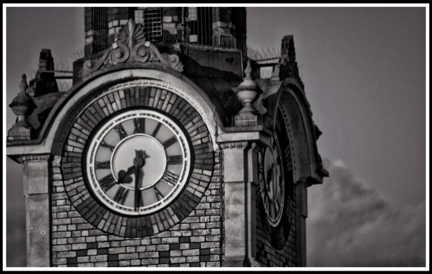 A close up black and white photo of the clock at the top of the tower