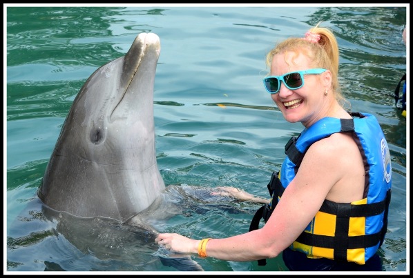 Sarah(on the right) in the water dancing with a Dolphin on her left