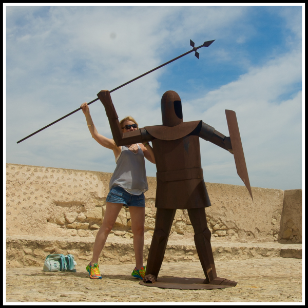 Sarah stood directly behind a warriour throwing a spear pretending to throw it too
