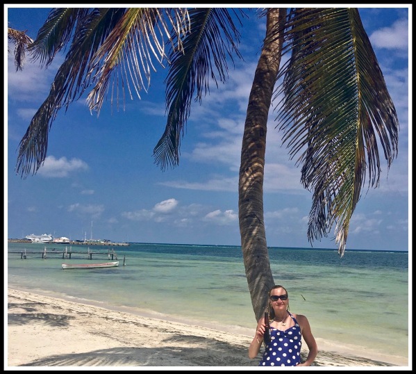 SARAH SAT AT THE BASE OF A BEAUTIFUL PALM TREE WITH THE AMAZING BLUE SEA AND YELLOW SAND LANDSCAPE BEHIND HER